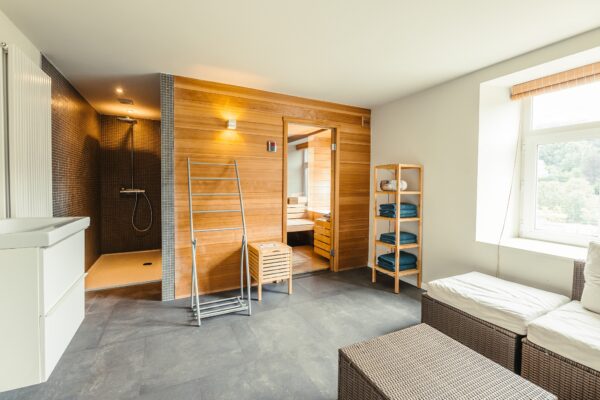 Relaxruimte met grote sauna, douche, wastafel en zithoek.